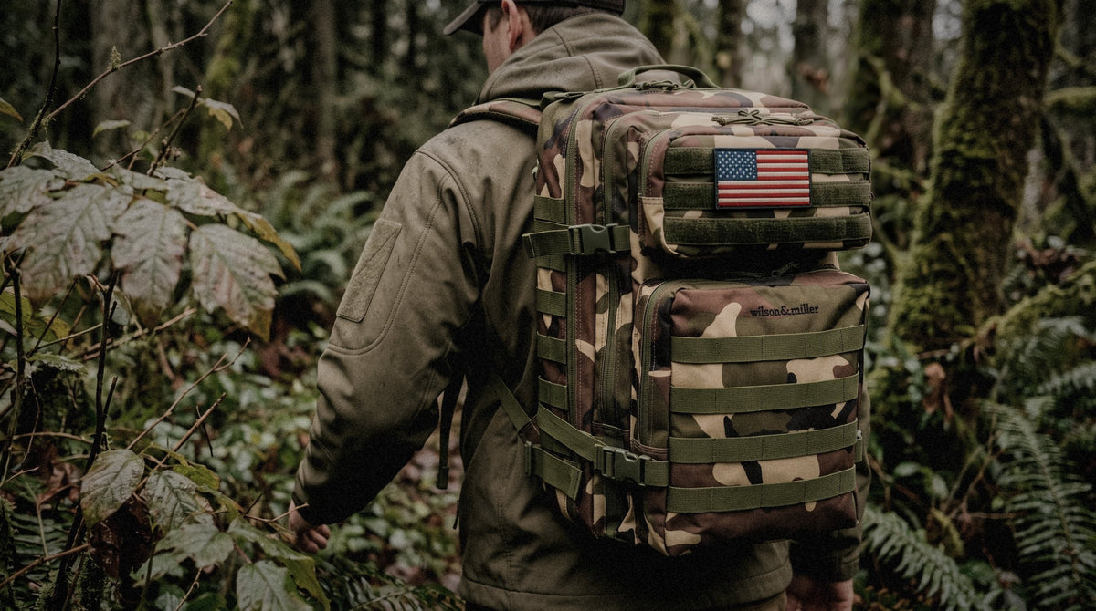 Garrison backpack in woodland camo with an American flag patch, carried through a forest